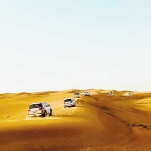 a group of jeeps driving through the sand dunes in desert safari from dubai | morning desert safari