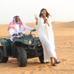 a couple standing with the double seat quad bike in Dubai desert