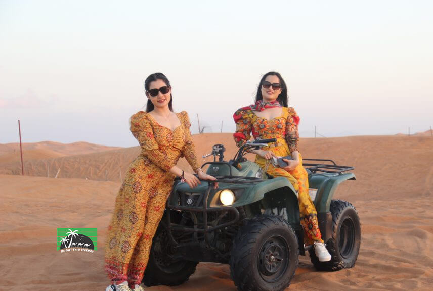2 ladies standing with double seat quad bike in desert safari